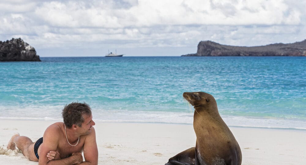 Ecuador, Galapagos Islands, Espanola, tourist and Galapagos sea lion on beach